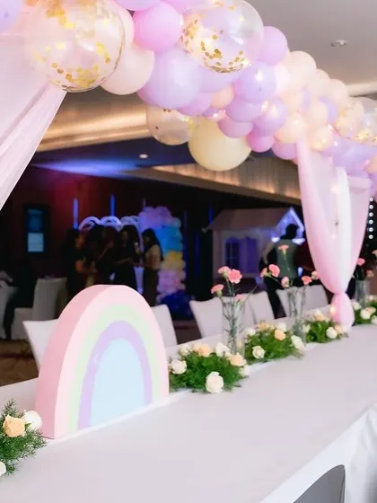 For the unicorn party, we designed a long guest table with a beautiful pastel balloon arch overhead and custom rainbow centerpieces. Every detail is planned to match the theme perfectly.