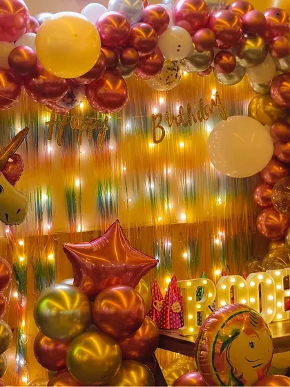 A closer look at the unicorn-themed decor for Roohika's first birthday. The combination of a shimmer curtain, fairy lights, and chrome balloons creates a magical and festive glow.