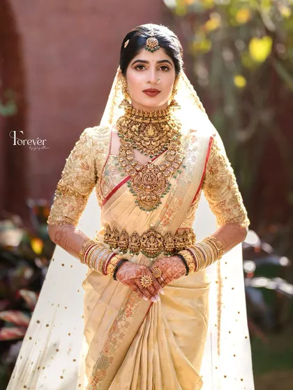 A powerful bridal portrait. The focus here is on the regal posture, the magnificent temple jewellery, and the confident yet serene makeup look.