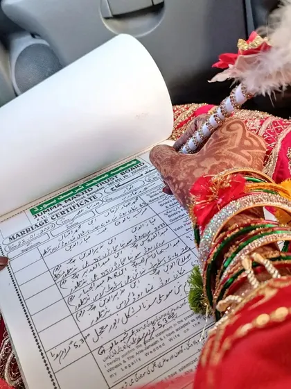 A close-up of the Nikkah-nama being signed, with the bride's intricate mehendi on full display.
