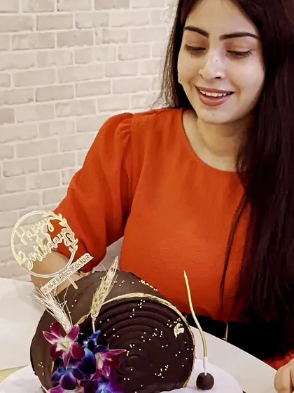 A happy client celebrating her birthday with one of my custom chocolate log cakes. Seeing the joy my creations bring is the best part of my job.