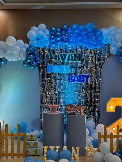 Here is a modern and stylish Boss Baby theme for a second birthday. I used a blue shimmer wall as the central backdrop, framed by a balloon arch in shades of blue and white, with custom neon lettering and a light-up number '2' to complete the look.