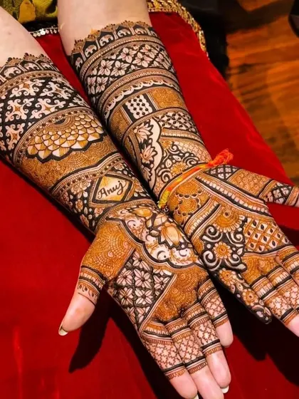 A beautiful example of incorporating a name, 'Anuj', into a full, dense bridal mehndi design.