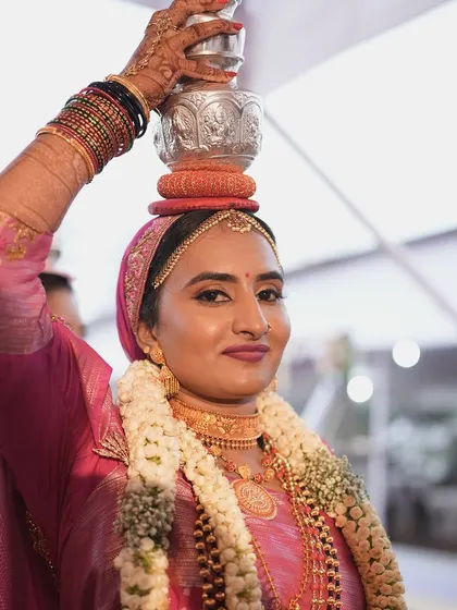 The bride participating in a traditional ritual. Her makeup is flawless, and she looks serene and happy.