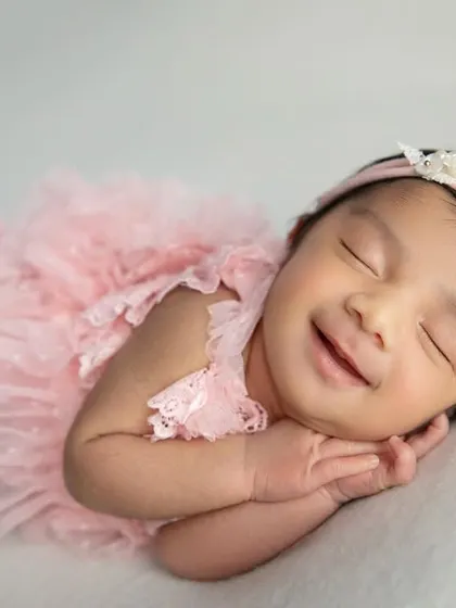 The best moment to capture. A big, happy, sleepy smile from a baby girl in her pink outfit. These are the moments that make parents' hearts melt.
