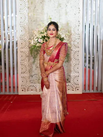 This bride chose a beautiful light pink and gold tissue saree for her reception. I created a matching blouse with delicate embroidery on sheer sleeves, adding a touch of modern elegance to her look.