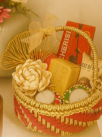 Our "Diwali Bliss" hamper comes in a red handcrafted jali basket. It's filled with Phool incense cones, decorative tea lights, and chocolate laddoos.