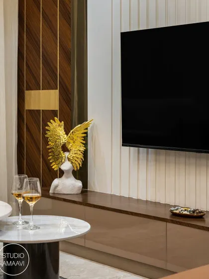 Details make the design. Here, a golden winged sculpture adds a touch of artistic flair to the entertainment console. The combination of a ribbed feature wall, glossy cabinetry, and marble tabletops showcases our focus on mixing textures and materials.