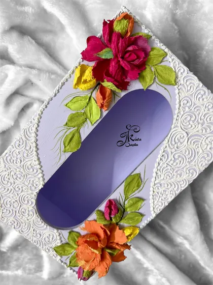 A top-down view of the lavender tissue box, showing the symmetrical arrangement of the floral sculptures and the intricate filigree pattern.
