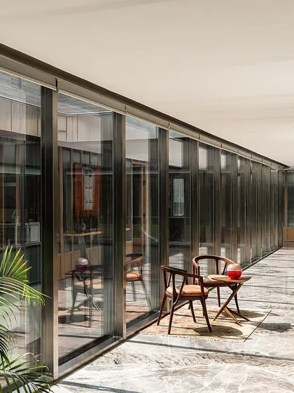 The top floor corridor is defined by a striking greyish-white marble floor and a fluted glass and wood paneled wall, setting a distinct, elevated aesthetic for the executive level.