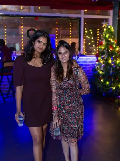 Two friends enjoying the festive Christmas decorations during a holiday party.