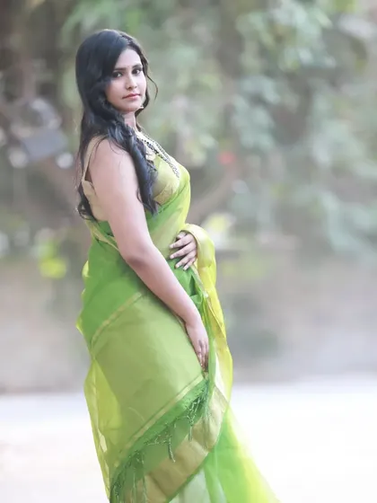 A simple and elegant outdoor portrait in a light green organza saree. The soft, natural light and blurred background make the model and the saree the main focus.