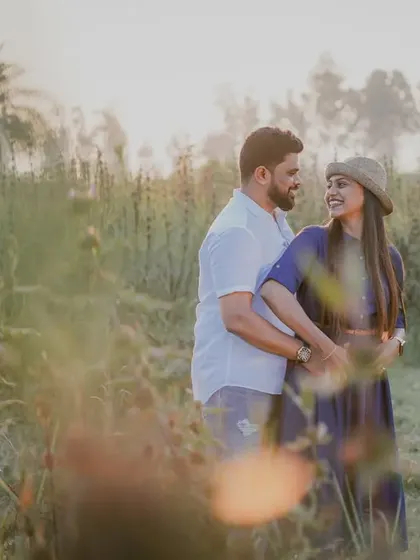 A sun-flared, romantic shot of the couple in a field at golden hour.
