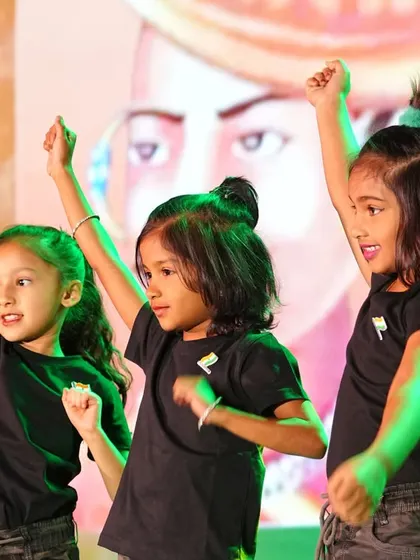 Three girls strike a powerful pose during their dance, their confidence shining on the Annual Day stage.