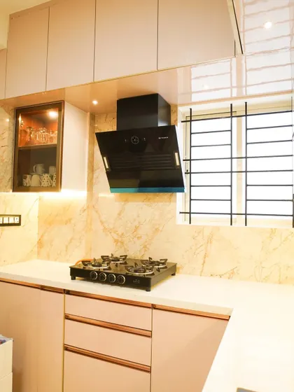 This elegant kitchen uses a soft, dusty pink laminate for the cabinets, paired with a white countertop and a beautiful marble-veined backsplash. The rose gold profile handles add a touch of sophisticated glamour.