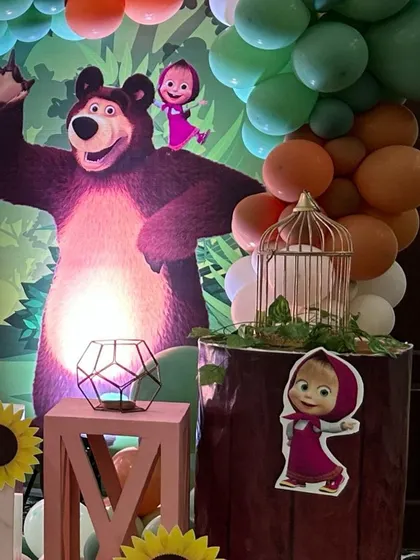 Another view of the Masha and the Bear party decor, focusing on the character cutouts and props that create an immersive forest scene.