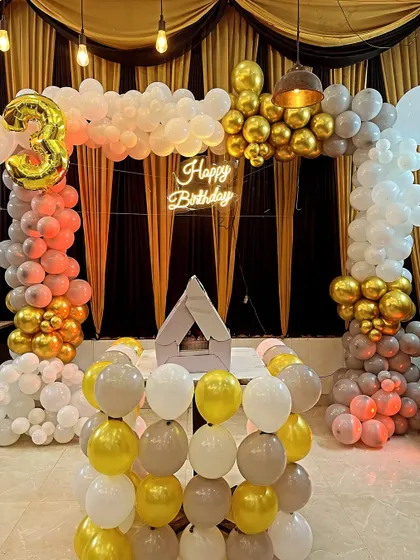 A jungle-themed 3rd birthday party setup in a living room, with a large backdrop and balloon arch.