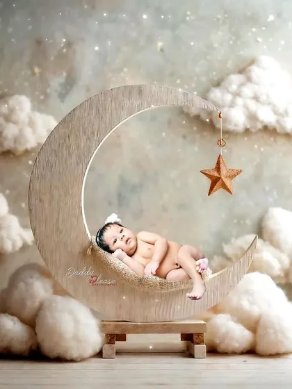 A peaceful newborn portrait featuring a baby sleeping on a wooden crescent moon prop, surrounded by soft, dreamy clouds. These sessions are designed to be calm and safe for your little one.