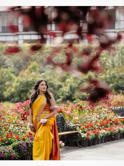 A beautiful portrait of the bride in her yellow saree amidst a garden of flowers.