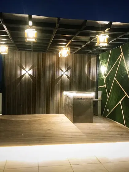 A beautiful pergola at night. We used a combination of WPC louvers for the back wall, a geometric artificial green wall, and multiple layers of lighting to create this dramatic effect.