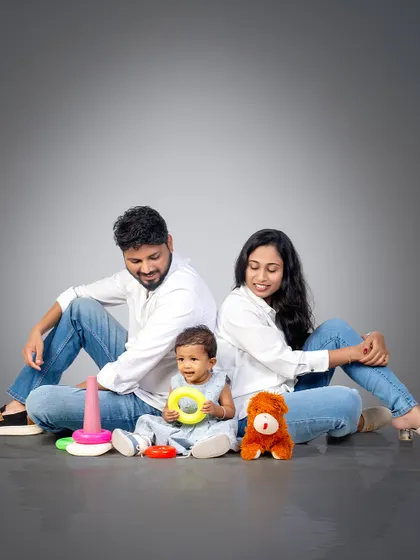 A playful family moment on the studio floor. The parents look on lovingly as their little one plays, a candid slice of family life.