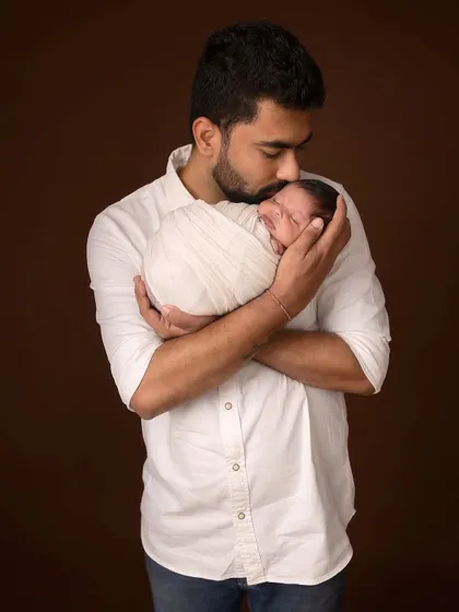 A father's gentle kiss for his newborn. This classic portrait against a simple backdrop emphasizes the powerful, protective love in this new relationship.