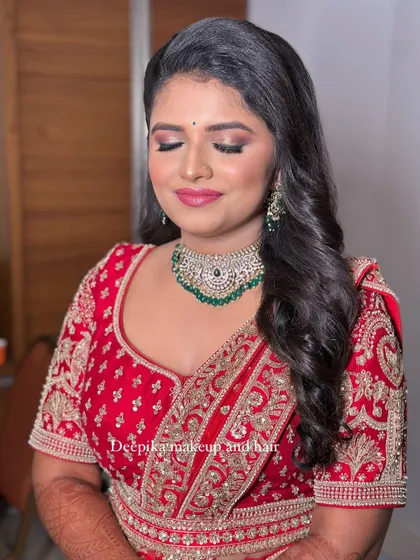 A close-up of the bride's makeup, featuring a soft smokey eye and a pink lip that complements her red outfit.