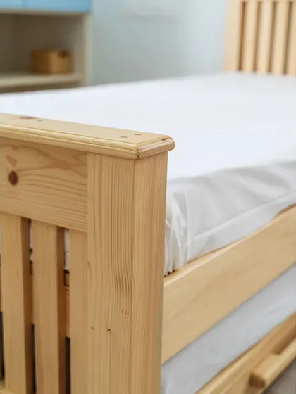 A detail shot of the corner of the pine wood bed, highlighting the quality of the joinery and the smooth finish of the wood.