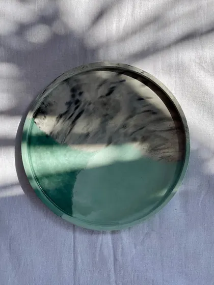 A round tray with a custom green and grey marbled pattern, catching the beautiful morning sun.