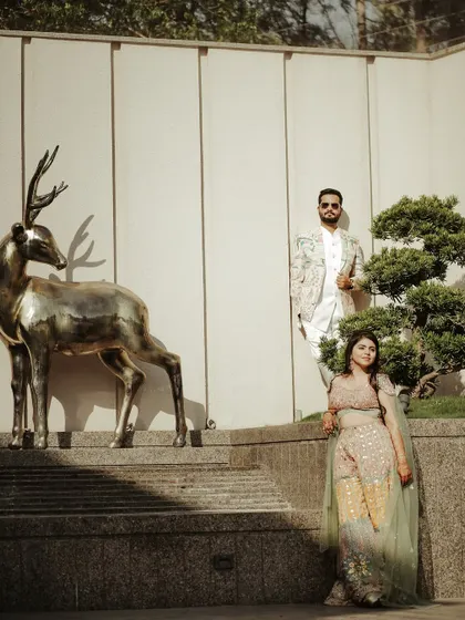 A stylish and unique portrait of the couple with modern art. Their poses are confident and relaxed, creating a cool, contemporary image in the bright sunlight.