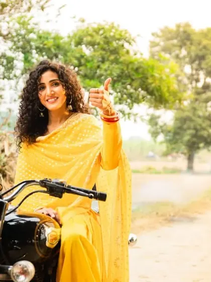 A vibrant outdoor shot for a two-wheeler finance ad, featuring a woman in a rural setting. This image is crafted to feel authentic and empowering.