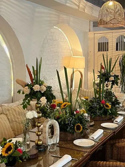 A beautiful tablescape for a baby shower at a restaurant. We used tall floral arrangements with sunflowers and roses to add color and life to the space.