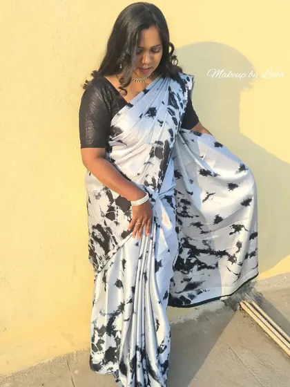 A full-length shot of a client in a modern black and white satin saree. The makeup is subtle yet polished, ideal for a cocktail party or evening event.