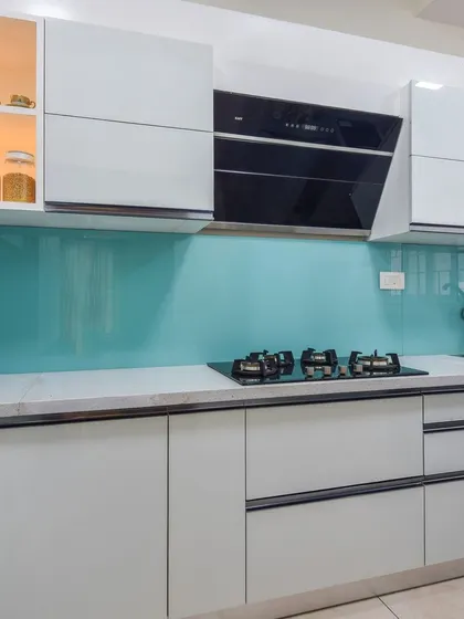 A view of the upper cabinets, one of which features internal lighting, perfect for showcasing special crockery. The white cabinets make the kitchen feel bright and spacious.