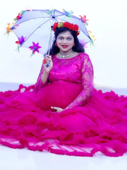 A playful maternity photo with the mother-to-be in a pink gown, holding a floral umbrella.