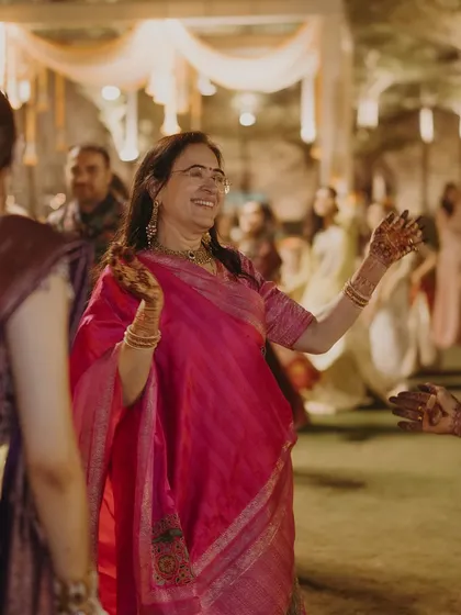 The mother of the bride enjoying the sangeet night. Her bright pink saree stands out, showcasing her vibrant personality and the celebratory spirit of the event.