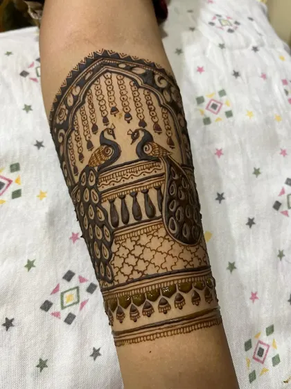 This section of a bridal arm features two peacocks facing each other, a classic symbol of love and beauty in mehendi art.