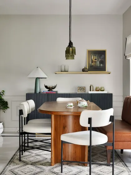This dining space from the Madras Home combines a leather banquette with modern chairs for a collected, eclectic look. The fluted black credenza provides storage and a surface for a curated display.