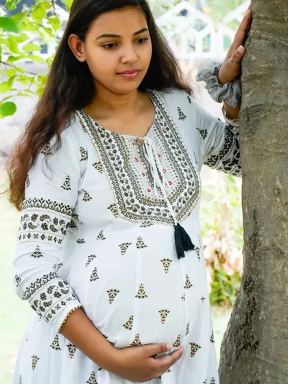 A candid shot of an expecting mother looking thoughtful while leaning against a tree. Our outdoor maternity sessions include a mix of posed and natural moments.