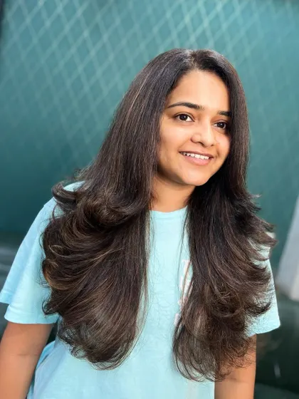 A happy client with her fresh, layered haircut and subtle brown highlights. The style is full of volume and movement.