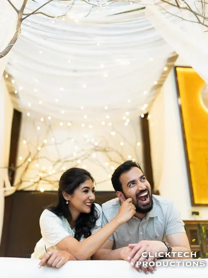A fun and candid moment of a couple laughing under a canopy of fairy lights, capturing their joyful interaction.