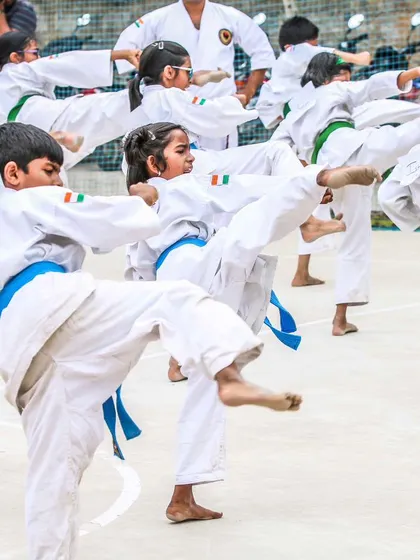 Young students practicing Mae Geri (front kicks) in unison. Synchronized practice helps build rhythm, balance, and precision in their techniques.