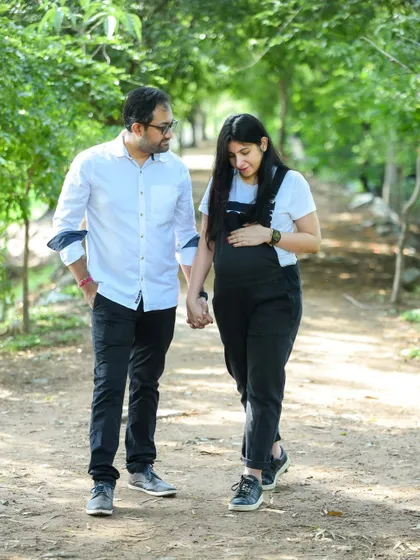 A casual and happy moment of a couple walking hand-in-hand through a park. This shot captures the simple joy of their journey to parenthood.