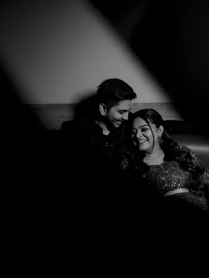 A candid black and white shot of the couple sharing a laugh during their reception party.