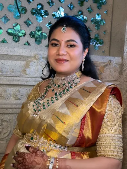 A clear, still image of the finished look. The makeup is perfectly balanced, with attention to the eyes, lips, and skin, complementing her diamond and emerald jewellery.