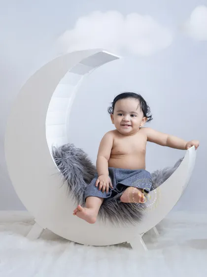 A bright and cheerful shot using our moon prop. This happy baby is surrounded by miniature houses and fluffy clouds, creating a whimsical and sweet village scene.