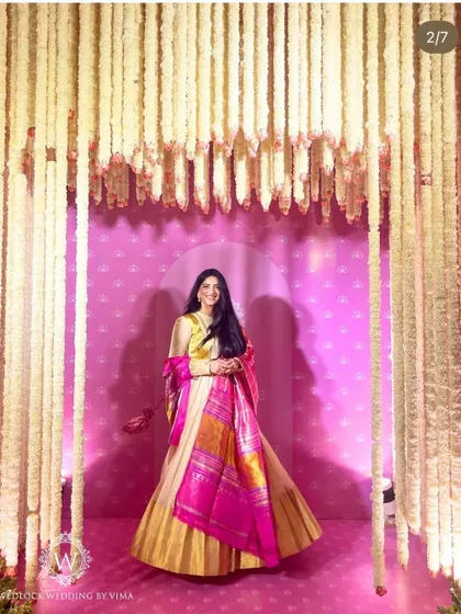 A guest poses within a photo booth framed by hanging jasmine garlands. This beautiful setup provided a perfect spot for memorable pictures at the half-saree function.