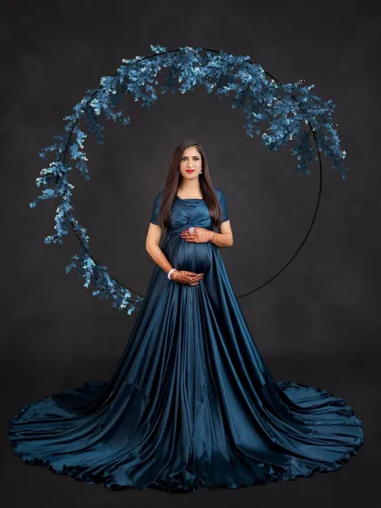Adding a prop like this floral ring creates a beautiful frame for your portrait. It complements the deep teal of the gown and adds a touch of botanical elegance.