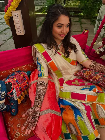 A lovely bride in a colorful outfit, her detailed storytelling mehndi on display.