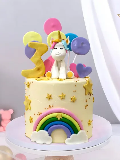 A dreamy unicorn cake for a 3rd birthday, featuring a rainbow, colorful balloons, and sparkling stars. This creation is full of magic and sweetness, perfect for a little believer.